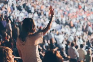 Una mujer de espaldas, levantando la mano en una multitud